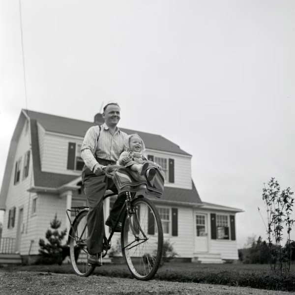 Original photograph of an adult and child on a bicycle outside a house